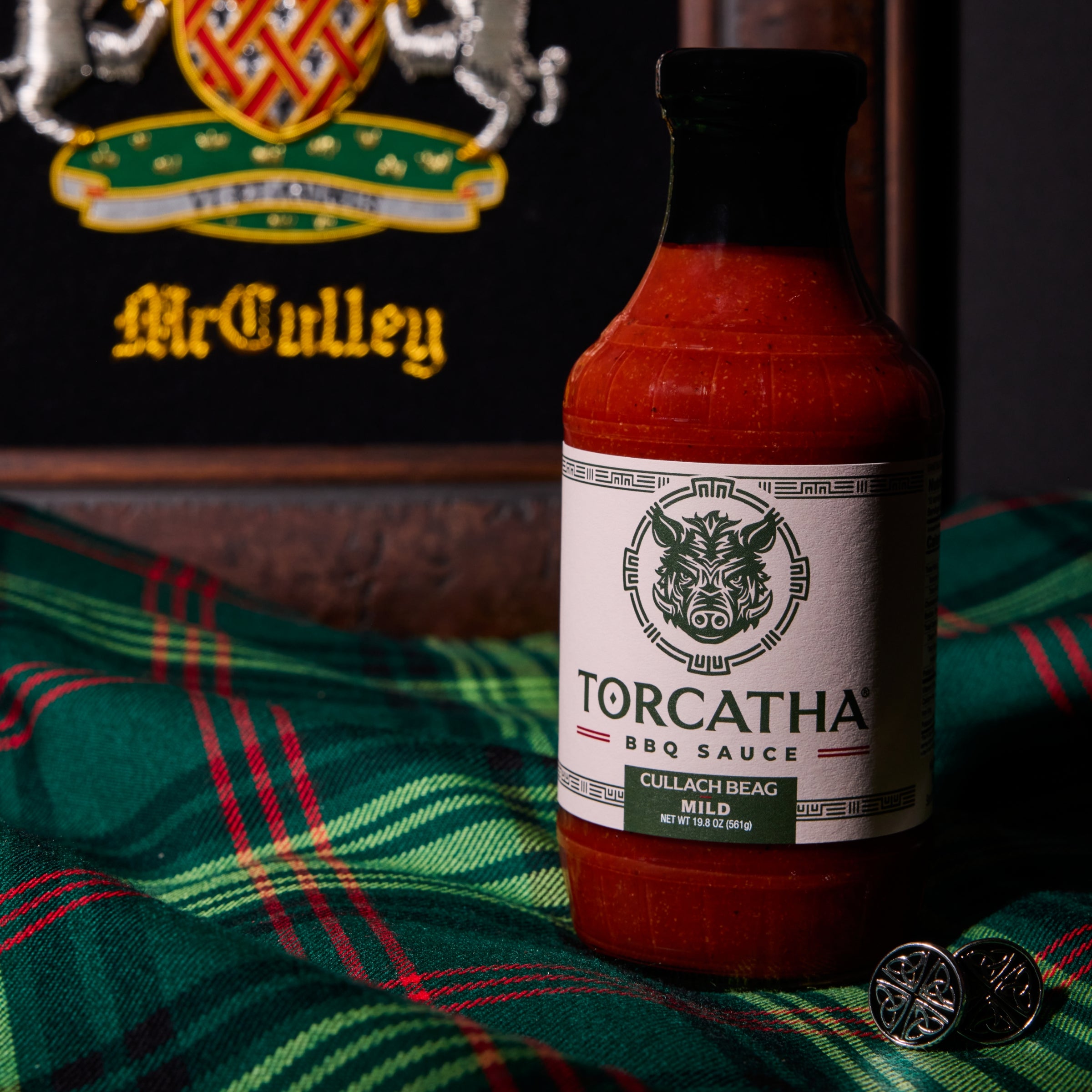 Bottle of Torcatha BBQ sauce on a plaid fabric with McCulley logo in the background