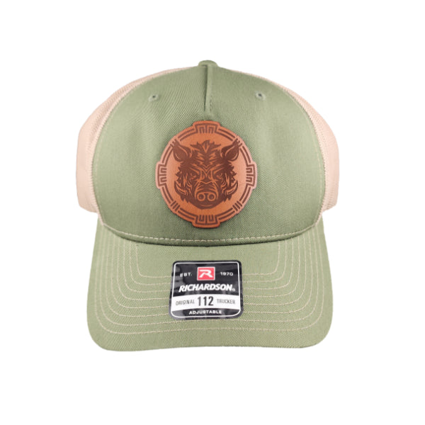 Green trucker cap with brown leather patch featuring the Torcatha Battle Boar, representing those who live with strength, honor, and flavor.