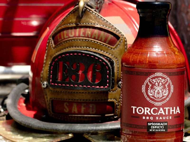 Firefighter helmet with the text "Lieutenant SAFD E36" next to a bottle of Spicy Torcatha BBQ Sauce.