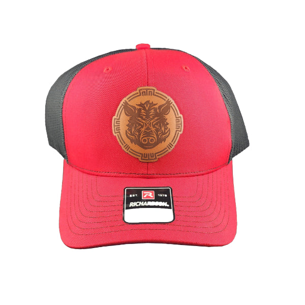 Red trucker cap with grey mesh and a brown leather Battle Boar logo, representing the Torcatha BBQ Sauce brand, on a white background.