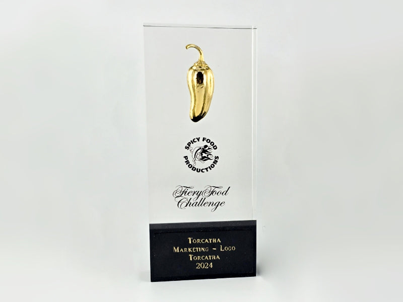 Rectangular glass trophy featuring a golden chili pepper for the 2024 Spicy Food Productions Fiery Food Challenge, an award given to Torcatha for marketing and logo design featuring the Battle Boar, representing the brand’s commitment to crafting award-winning barbecue sauce.