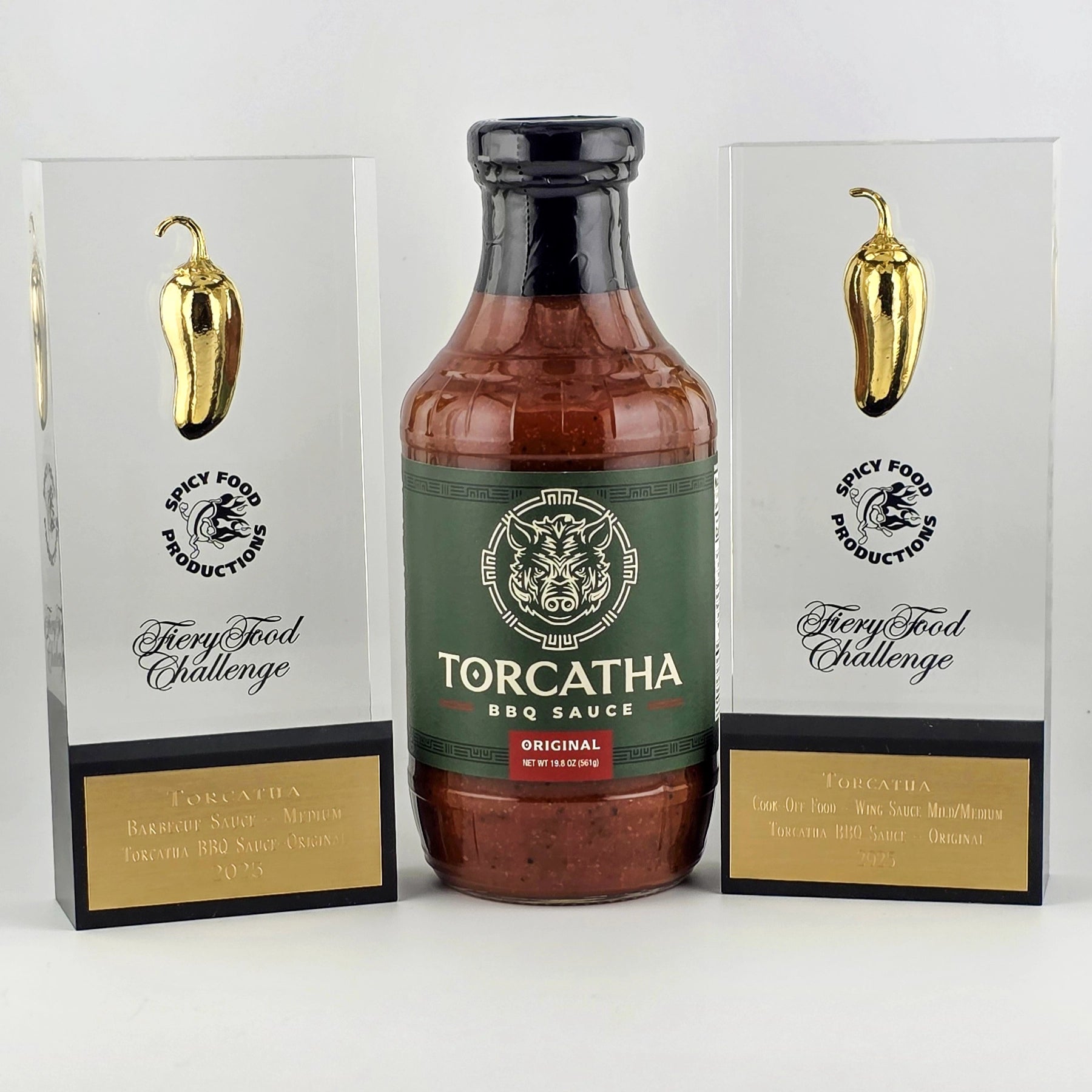 Torcatha Texas BBQ Sauce Original flavor positioned between two rectangular glass trophies featuring golden chili peppers and text that reads, "Spicy Food Productions Fiery Food Challenge."