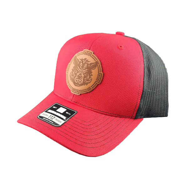 Side view of a red trucker cap with grey mesh and a brown leather Battle Boar logo, representing the Torcatha BBQ Sauce brand, on a white background.